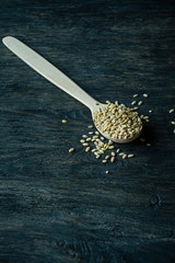 Pearl barley in a wooden spoon on a dark wooden background. Side view.
