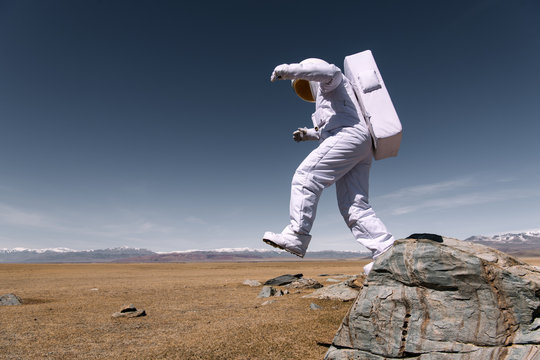 Astronaut jumping down from mountain