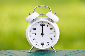 White alarm clock on green background. 