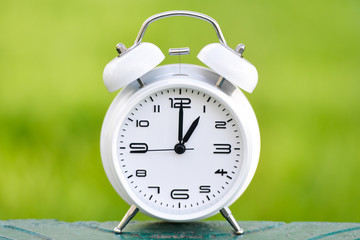 White alarm clock on green background. 