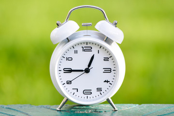White alarm clock on green background. 