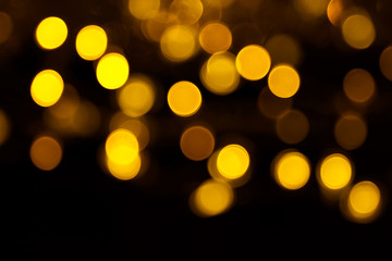 Abstract gold bokeh on black background. Defocused yellow lights, abstract texture