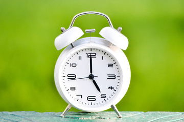 White alarm clock on green background. 