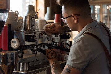Tattooed barista working with machine