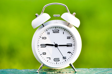 White alarm clock on green background. 