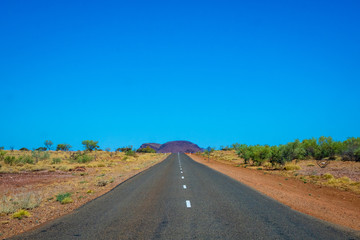Fototapeta na wymiar Australian road leading towards small mountain in Karijini National Park