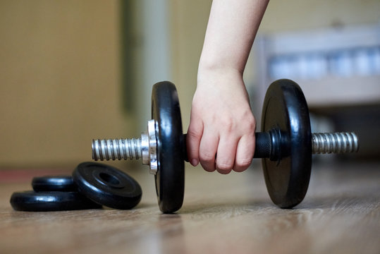 The Hand Of The Girl Takes A Dumbbell From The Floor At Home, Home Sports, Healthy Lifestyle