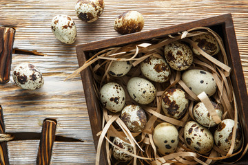 Quail eggs. Flat lay composition with small quail eggs in the wooden box on the natural wooden background. One broken egg with a bright yolk.