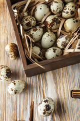 Quail eggs. Flat lay composition with small quail eggs in the wooden box on the natural wooden background. One broken egg with a bright yolk.