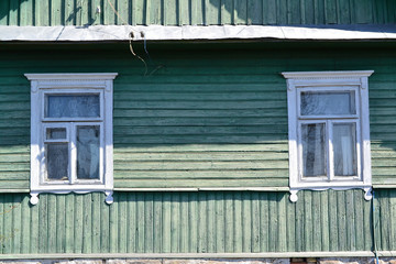 Vintage windows jamb of traditional old wooden russian house in village, shabby background of teal color, close up with copy space