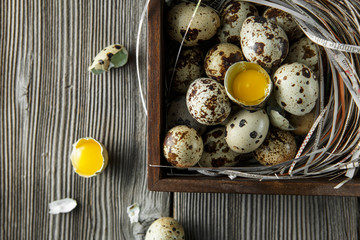 Quail eggs. Flat lay composition with small quail eggs on the natural wooden background. One broken...