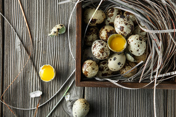 Quail eggs. Flat lay composition with small quail eggs on the natural wooden background. One broken...