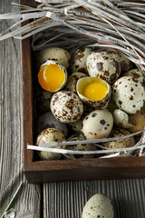Quail eggs. Flat lay composition with small quail eggs on the natural wooden background. One broken...