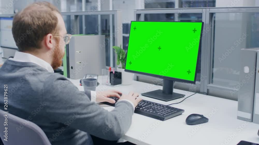 Poster Over the Shoulder Shot of Motivated Office Worker Using Green Mock-up Screen Desktop Computer in the Big Bright Open Space Office