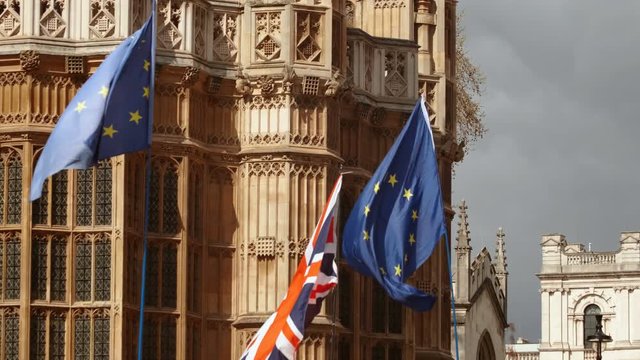 Close-up shot of EU flags waving in slow motion against the backdrop of Westminster Palace in London, England, UK