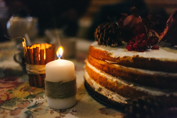 Pomegranate layered cake in the light of a thick wax candle wrapped in a hemp cord