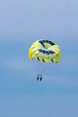 Two people parasailing above the Gulf of Mexico near Englewood, Florida, USA, in early spring, with soft clouds and blue sky as backdrop