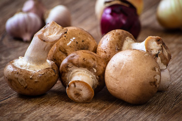 Fresh whole brown champignon mushrooms on vintage wooden table