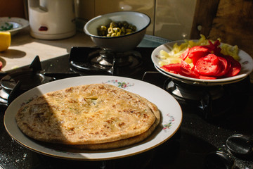 Naan cooked at home on a white plate on a gas stove.