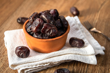 Fresh organic dates fruits in a clay bowl on wooden table
