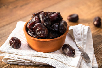 Fresh organic dates fruits in a clay bowl on wooden table