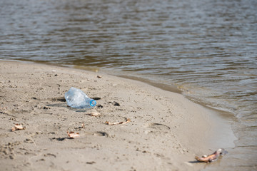 Fototapeta na wymiar smashed pet disposable plastic bottle on beach sand. Plastic pollution