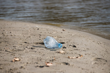 smashed pet disposable plastic bottle on beach sand. Plastic pollution