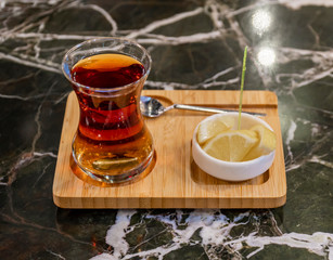 Turkish tea in traditional glass on wooden plate closeup