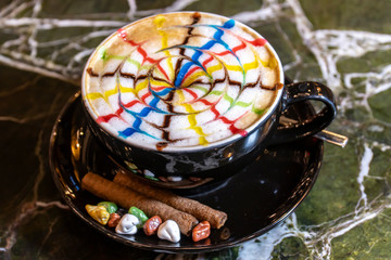 Hot Cappuccino coffee with colorfull caramel motif art floating on top and coffee beans. Coffee break at retro style coffee shop.