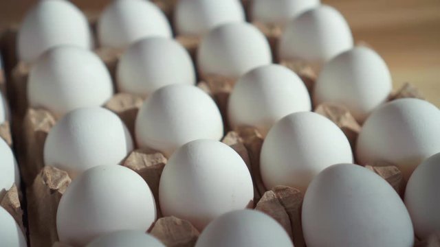 Lots of eggs in a cardboard box on the table.