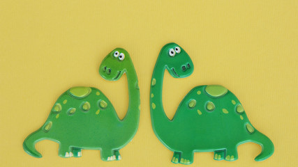 two green dinosaurs on a yellow background