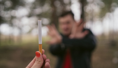 Man refusing to take cigarette. Crop female hand offering cigarette to male meeting stop gesture...