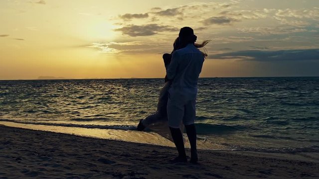 Romantic couple twirling around on a sunset beach - slow motion