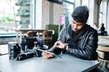 Smart young asian man photographer working with tablet during sitting at cafe and looking at his watches.