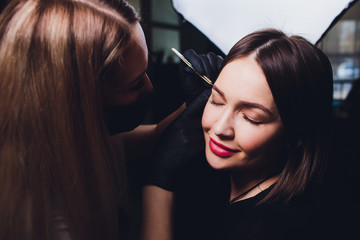 Cosmetologist making eyebrows design. Attractive woman getting facial care at beauty salon. Perfect...