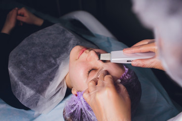 Hardware cosmetology. Beautician makes chromotherapy ultrasound cleaning the client's face. Skin...