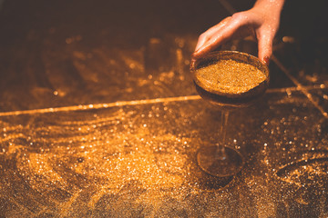 Golden cocktail glass at the bar. Young women's hand holding a martini glass with a golden stardust...