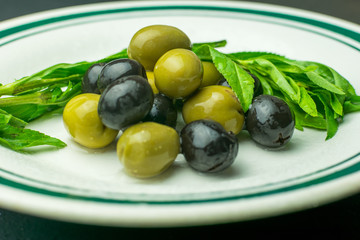 Fresh green and black olives served on a white porcelain plate