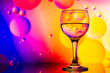 transparent glasses with water and oily drops on colorful background 