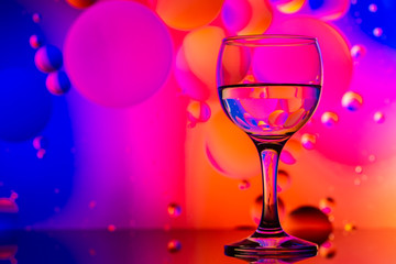 transparent glasses with water and oily drops on colorful background 