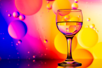 transparent glasses with water and oily drops on colorful background 
