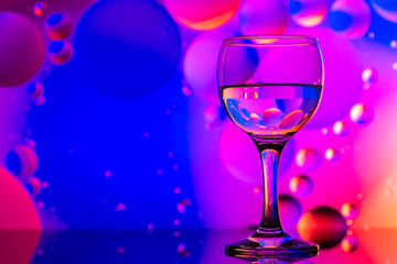 transparent glasses with water and oily drops on colorful background 