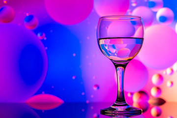 transparent glasses with water and oily drops on colorful background 