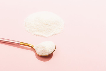 Collagen powder on pink background. Extra protein intake. Natural beauty and health supplement for skin, bones, joints and gut. Plant or fish based. Flat lay, top view. Copy space.