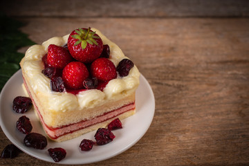 strawberry leyer cake topping strawberry putting on the white plate on the wood table background.