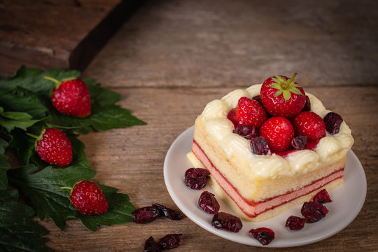 strawberry leyer cake topping strawberry putting on the white plate on the wood table background.