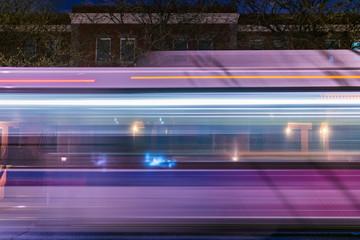 New York City public transportation MTA buss swooshing down a nighttime street in Harlem, NYC, USA
