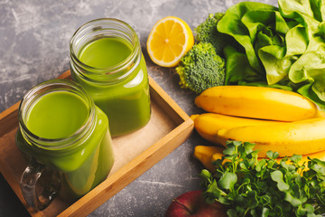 Two green smoothies in moody dark background.