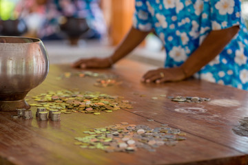 Obraz premium background of blurred coins, Thai currency placed on a wooden table for people to exchange for merit making according to various festivals (Songkran, New Year, Birthday) for the prosperity in life.