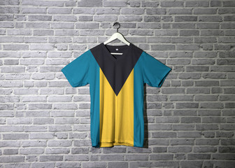 Bahamas flag on shirt and hanging on the wall with brick pattern wallpaper.